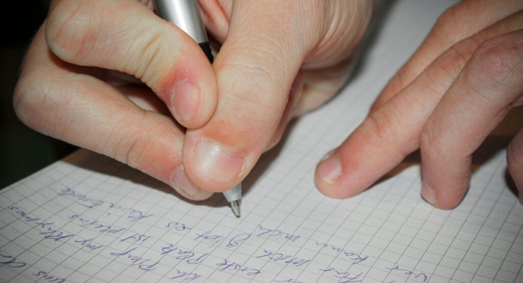 person writing down a song lyrics